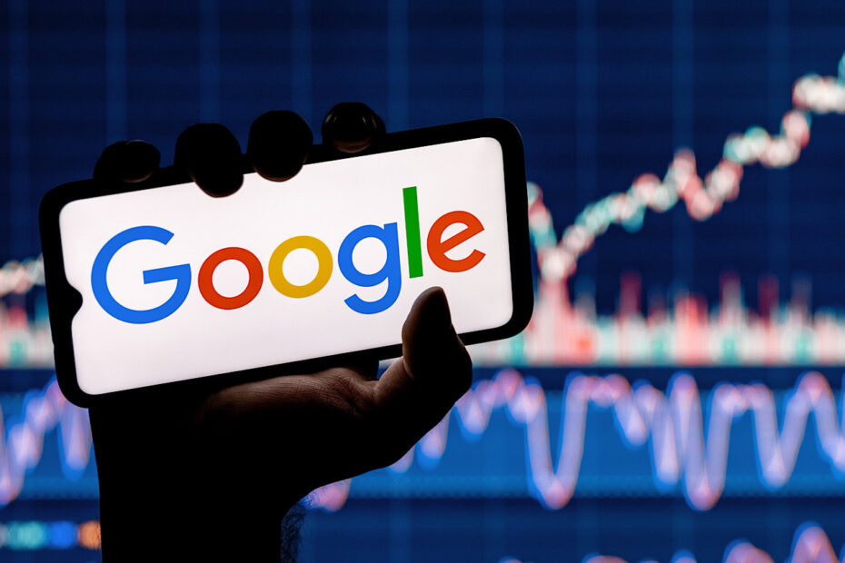 A person holding a smartphone displaying the Google Gemini Era logo, with a blurred background of stock market charts.